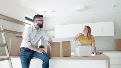 Couple unpacking moving boxes in new kitchen