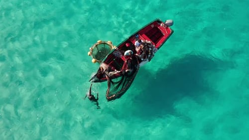 Top down view of African fishermen fishing in colorful turquoise water. Red fishing boat. Calm trans