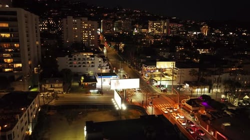 Forwards Fly Above Night City Traffic in Illuminated Streets and Buildings with Lighted Windows