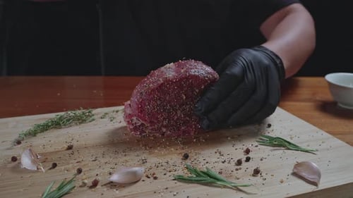 Chef seasons raw fresh tenderloin steak on a wooden cutting board, slow motion, close up