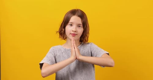 Pleading Teen Girl on Yellow Studio Background Wish and Praying