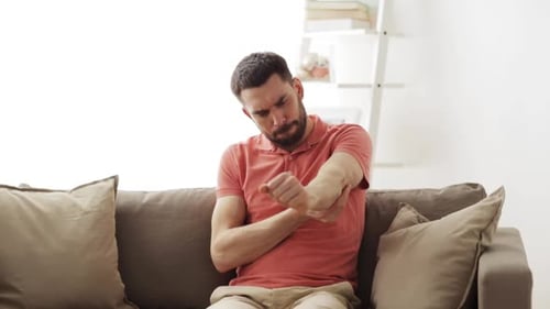 Man Rubbing Sore Elbow in Living Room