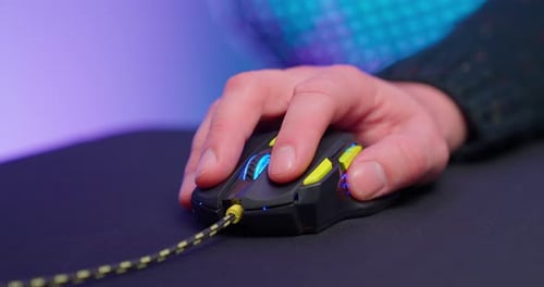 Hand Clicking Glowing Gaming Mouse on Black Mousepad