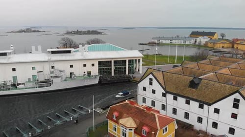 Aerial footage of a docked Swedish military ship next to a museum with old military flight hangars i