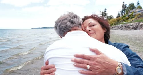 Happy senior asian couple embracing and kissing on a sunny beach vacation