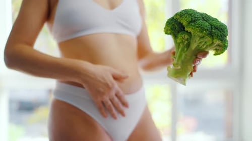 Una mujer sostiene un brócoli en la mano: concepto de alimentación y digestión saludables