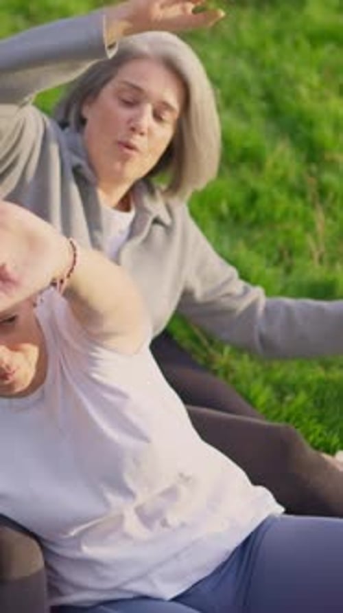 Two Senior Women Exercise Together in a Green Field