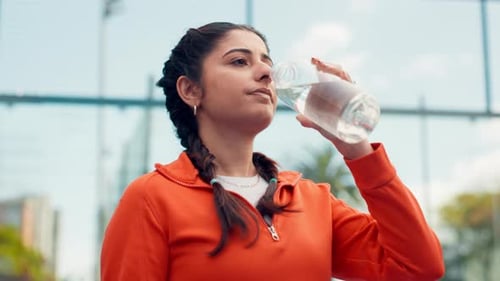 Woman Drinks Water After Exercising Outdoors in City