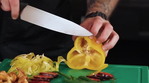 Man Slices Yellow Pepper in Kitchen