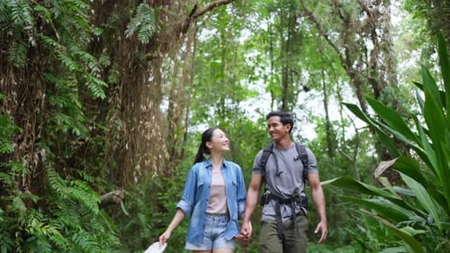 4K Young Asian couple hiking together in tropical forest.