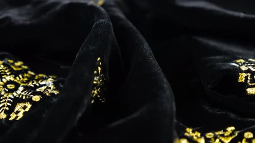 Luxurious black silken textile fabric velvet decorated with gold embroidery. Textile background