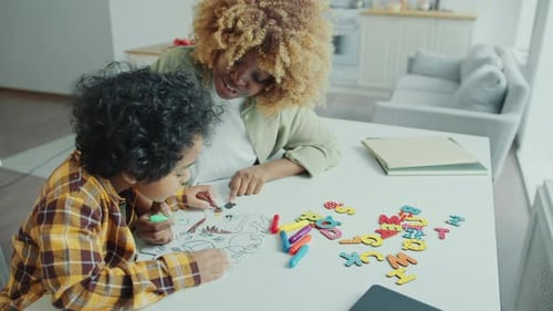 Woman and Child Coloring Together at Table Indoors