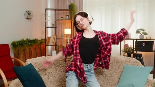 Young Woman Dancing with Headphones on Couch