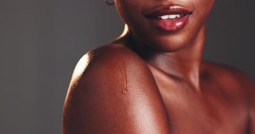 Studio, black woman and skincare with oil for shoulder, dermatology and clean shine for wellness