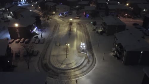 Snowplow Tractor Clearing Snow On Street At Night. Saint-Constant, Quebec, Canada. aerial shot
