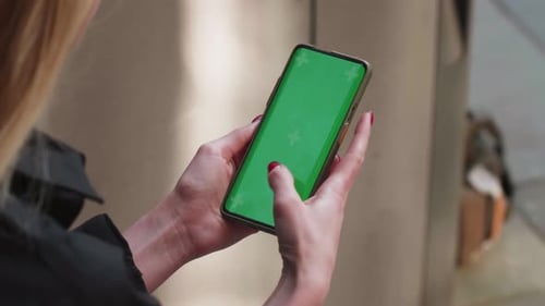 Woman's Hand Holding Mobile Phone with Green Screen Blurred Background Woman Using Cellphone