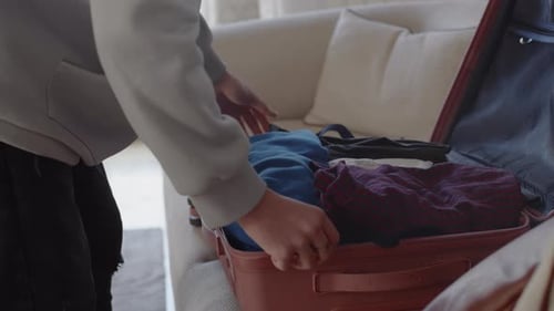 Person Packing Suitcase for Travel in Home