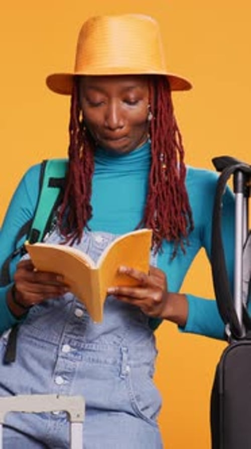 Traveler Reads Book While Sitting on Suitcase