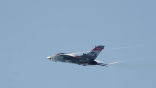 Military Jet Flying Through Blue Sky with Smoke