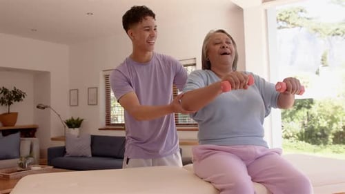 Male Trainer Assists Senior Female with Dumbbell Exercise