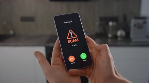 Hands Hold Phone with Scam Alert in Kitchen