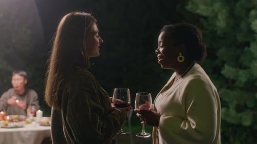 Multiethnic Women Talking and Drinking Wine at Cozy Outdoor Dinner Party