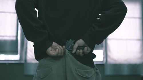 The male assassin put the gun in the rim of his pants, covered his hood