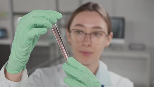Close-up of Young Scientist Intently Examening Test Tube with Liquid in Lab