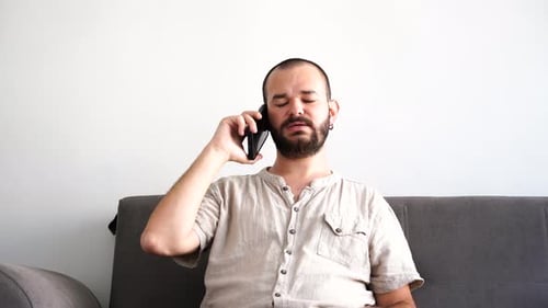 Man Talking on Phone While Sitting on Couch
