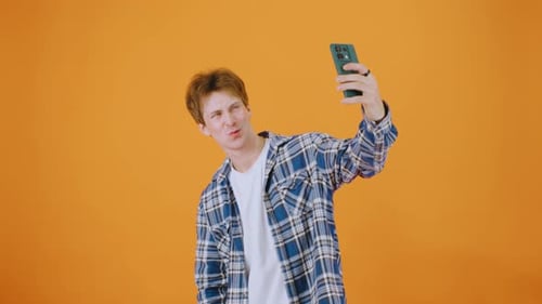 Young Man Taking a Selfie Against Orange Background