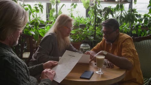 Three Friends Choosing Food from Menu in Pleasant Green Cafe