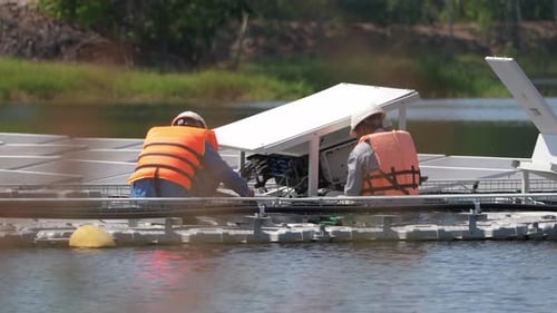 Floating Solar Panel on the pond. Worker is service and check on floating solar photovoltaic panels.