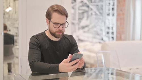 Man Using Smartphone at Table Indoors