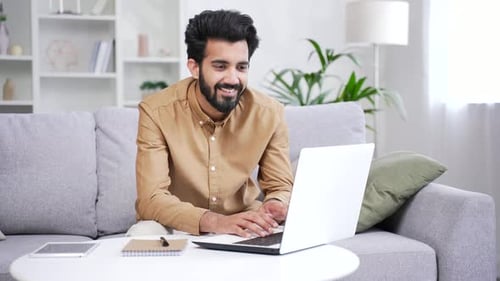Young Adult Types on Laptop at Home on Couch