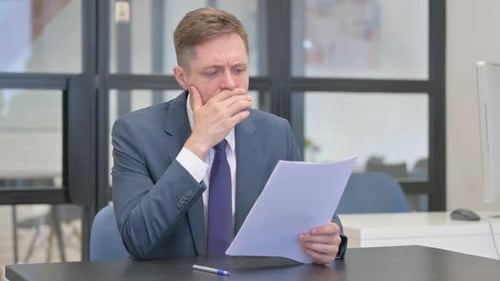 Worried Businessman Reviews Documents in Office Setting