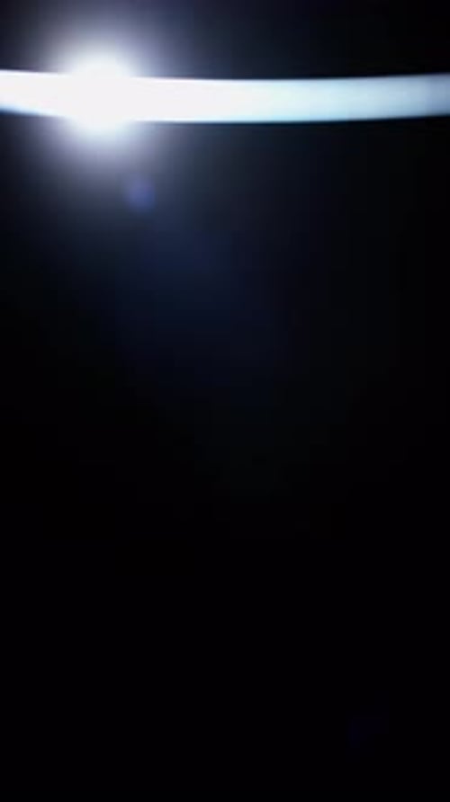 Radiant Lens Flare Moving Smoothly Across The Top In Darkness