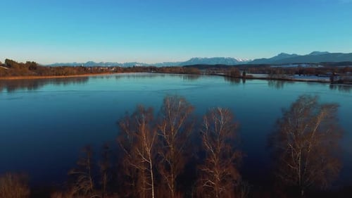 4K UHD aerial drone flight moving forwards above an icy frozen lake and tree tops in Bavaria close t