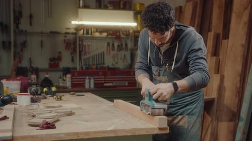 Adult Craftsman Sanding Wood in Workshop