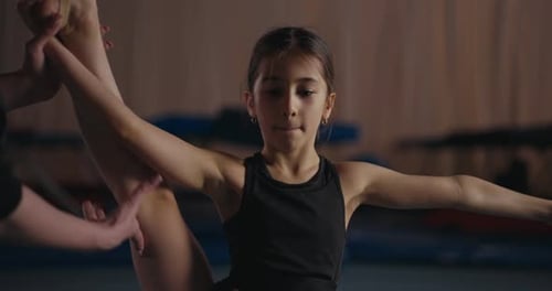 Close Up of a Little Girl Gymnast Doing Stretches and Raising Her Leg Up During a Gymnastics Class