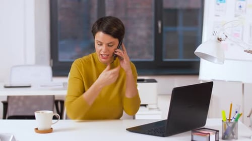 Hispanic businesswoman working with laptop and smartphone drinking coffee at office