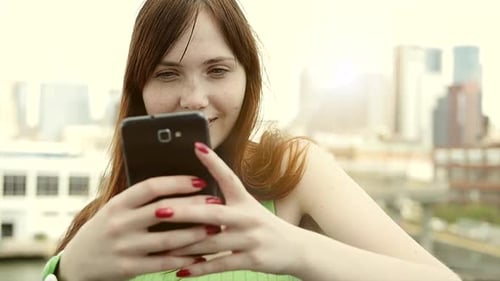 Smiling Woman Using Phone in City Environment