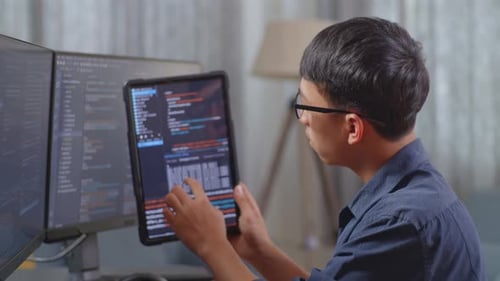 Asiatischer Jungenprogrammierer betrachtet die Datenbank auf dem Tablet, während er eine App für die Entwicklung eines Softwareingenieurs erstellt
