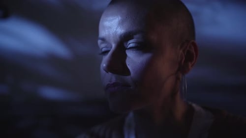 Primer plano de una mujer adulta caucásica afeitada siente soledad y depresión sola en un cuarto oscuro de su casa