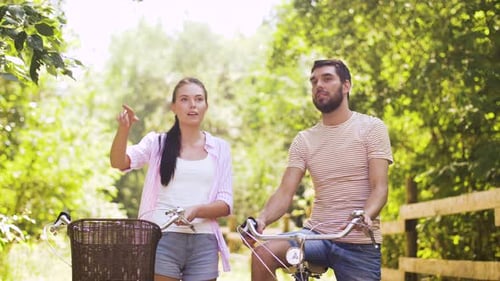 Conceito de pessoas, lazer e estilo de vida - jovem casal feliz com bicicletas conversando