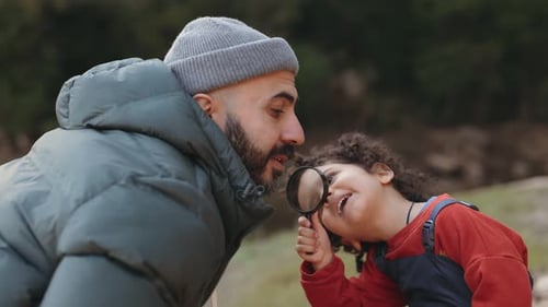 Père et fils explorant la nature ensemble avec une loupe