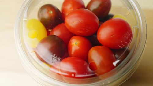 Tasty red and yellow tomatoes in a plastic cup with cover, healthy vegetable for take away, close up