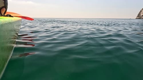 Sea Water Surface Camera Flies Over the Calm Azure Sea with Volcanic Rocky Shores on Background