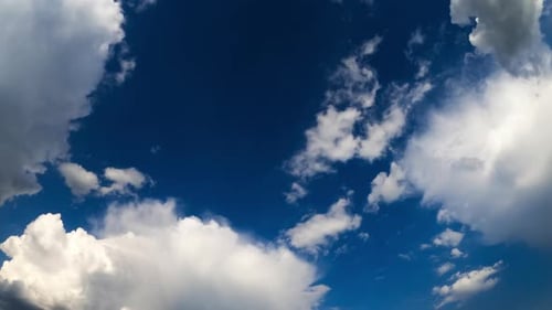 Deep blue sky with fluffy soft clouds. Soft white clouds transform in the atmosphere. Timelapse.