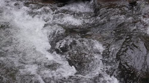 Zeitlupe von Flusswasser, das über Felsen spritzt, mit klaren Details und natürlichem Fluss