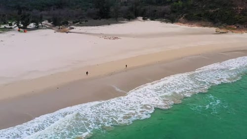 Camping tents on white sandy beach of tropical island washed by turquoise sea waves in Sai Kung, Hon